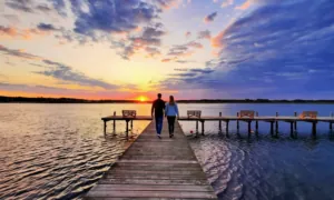 Couple enjoying a sunset walk on the waterfront dock at Tom's Cove Park, a waterfront campground on Chincoteague Island near Assateague Beach.